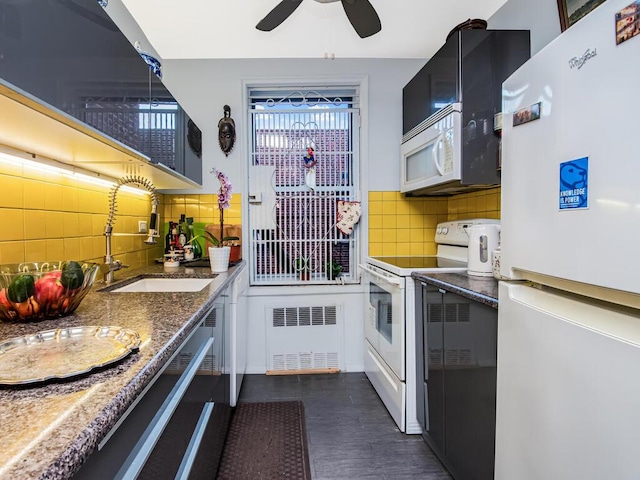 kitchen with sink, radiator, pendant lighting, white appliances, and backsplash