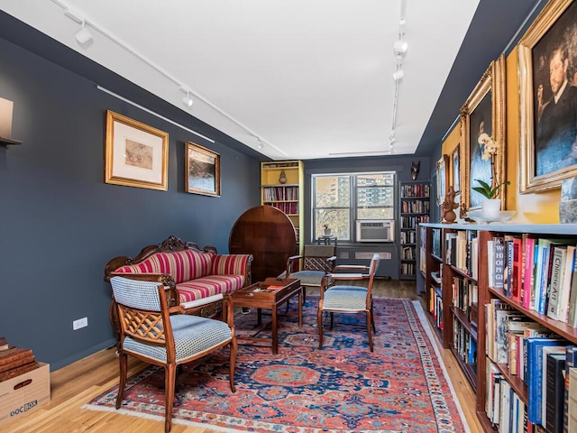 sitting room with hardwood / wood-style floors, track lighting, and cooling unit