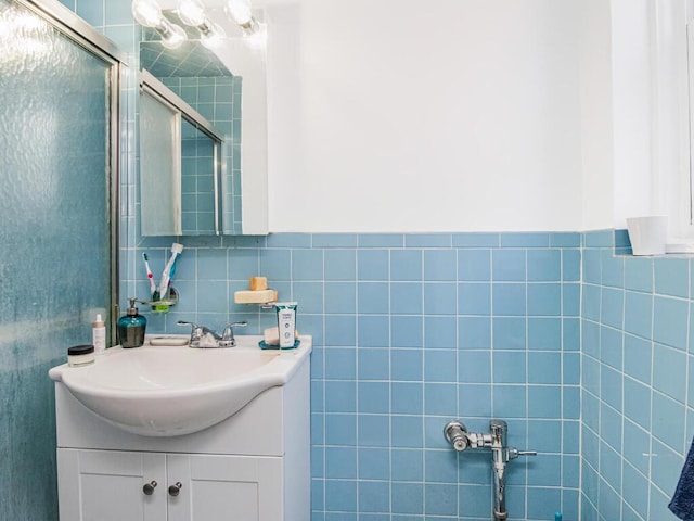 bathroom with a shower with door, vanity, and tile walls