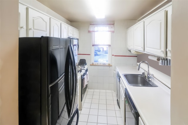 kitchen with sink, light tile patterned floors, white cabinetry, tile walls, and black appliances