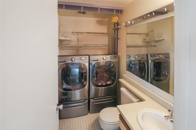 clothes washing area with sink, tile patterned floors, and washer and clothes dryer