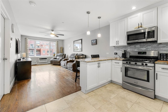 kitchen featuring pendant lighting, kitchen peninsula, white cabinets, and appliances with stainless steel finishes