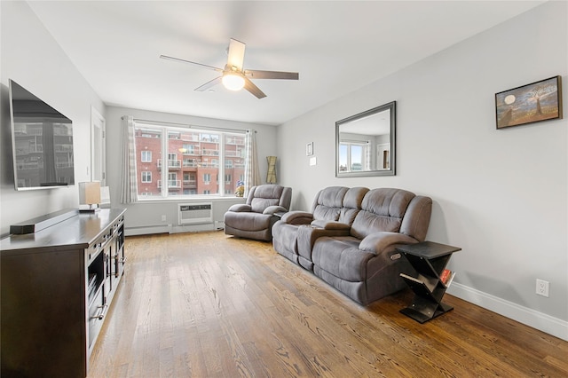 living room with a wall mounted AC, ceiling fan, and light hardwood / wood-style flooring