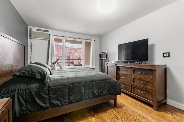 bedroom with light hardwood / wood-style flooring and a wall mounted AC