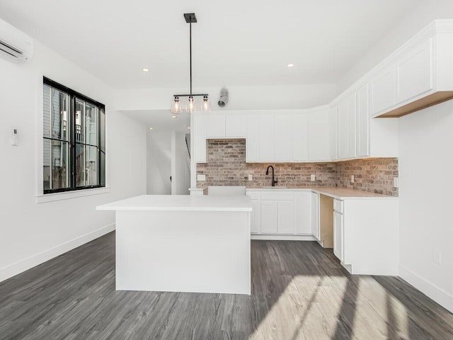 kitchen with pendant lighting, sink, white cabinets, a center island, and a wall unit AC