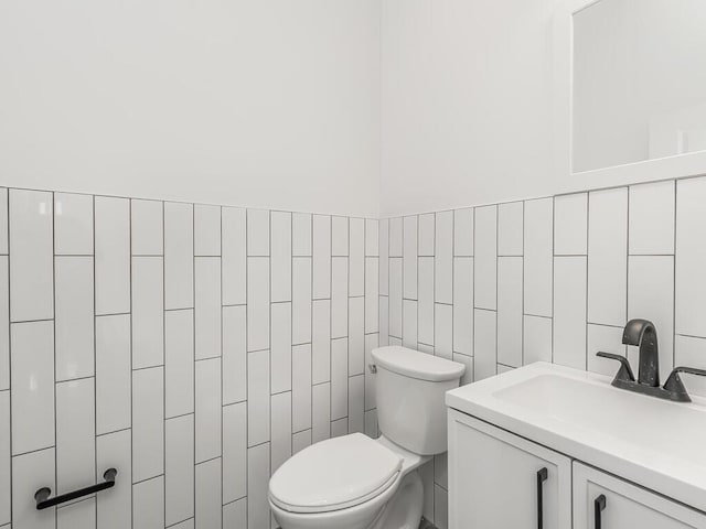 bathroom with vanity, tile walls, and toilet