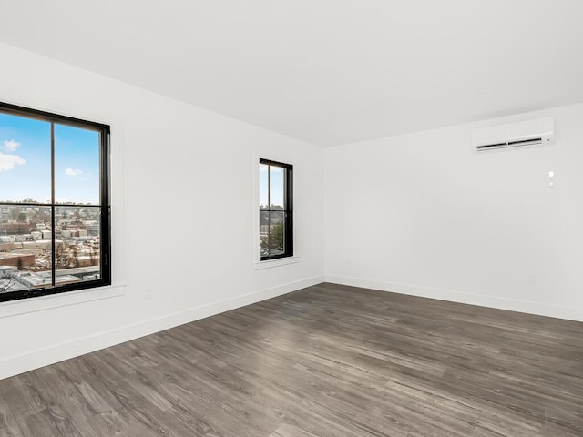 empty room with dark hardwood / wood-style flooring, a wall mounted AC, and a wealth of natural light