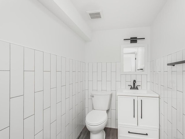 bathroom featuring tile walls, vanity, and toilet