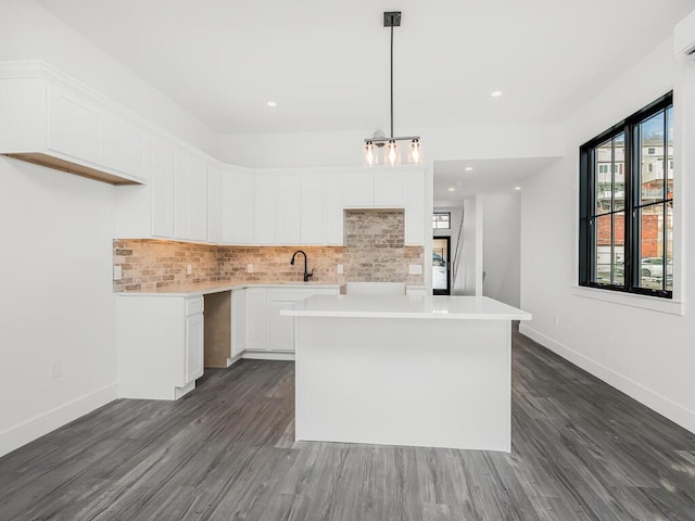 kitchen featuring pendant lighting, sink, backsplash, white cabinets, and a kitchen island