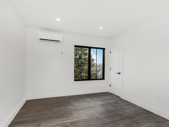 empty room featuring an AC wall unit and dark wood-type flooring