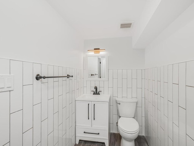 bathroom with vanity, tile walls, and toilet