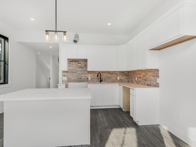 kitchen with pendant lighting, backsplash, white cabinetry, and a kitchen island