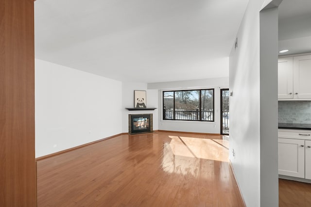 unfurnished living room with wood-type flooring and a tiled fireplace