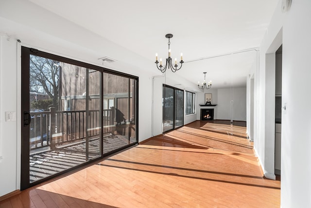 empty room with hardwood / wood-style floors and an inviting chandelier