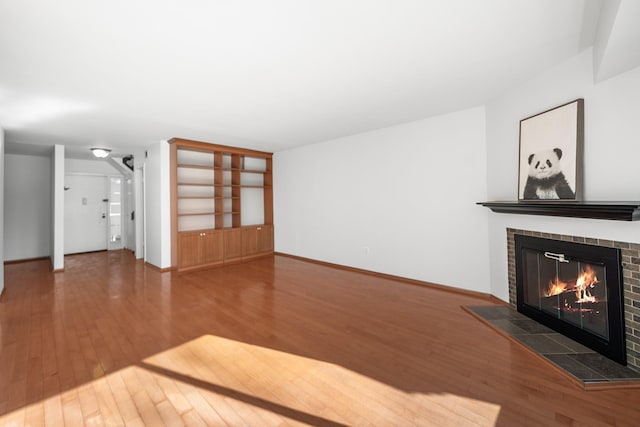 unfurnished living room featuring wood-type flooring and a tile fireplace