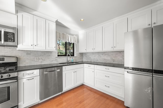 kitchen featuring sink, white cabinets, decorative backsplash, stainless steel appliances, and light hardwood / wood-style flooring