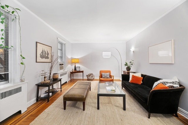 living room with ornamental molding, radiator heating unit, and light hardwood / wood-style floors