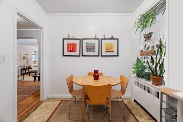 tiled dining room with radiator and crown molding