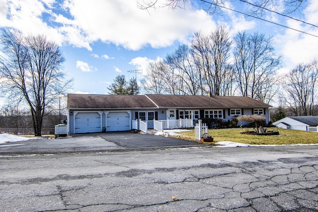 single story home featuring a garage, a front yard, and covered porch