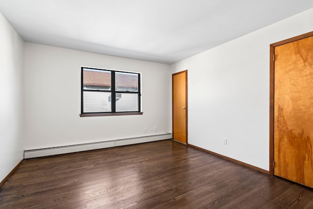 unfurnished room with dark wood-type flooring and baseboard heating