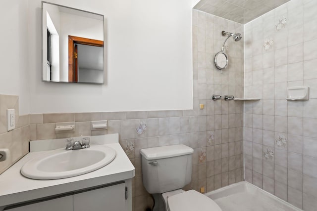 bathroom with tiled shower, vanity, toilet, and tile walls