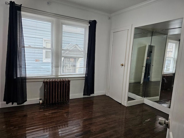 empty room featuring crown molding, dark hardwood / wood-style floors, and radiator