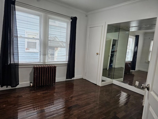 spare room with crown molding, dark wood-type flooring, and radiator heating unit