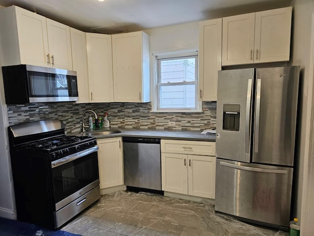 kitchen with appliances with stainless steel finishes, sink, white cabinets, and decorative backsplash