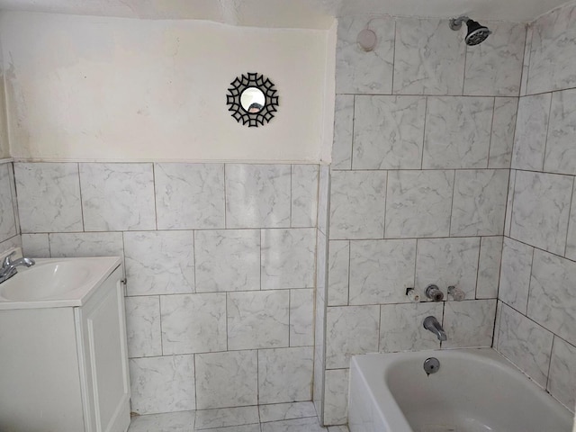 bathroom with vanity, tiled shower / bath combo, and tile walls