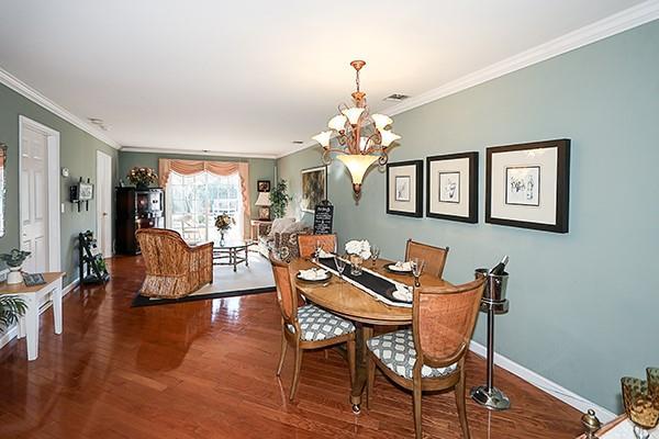 dining area with ornamental molding, hardwood / wood-style floors, and a notable chandelier