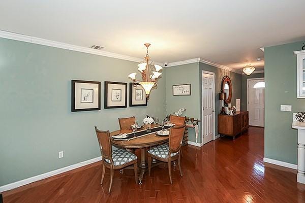 dining area featuring a notable chandelier, ornamental molding, and dark hardwood / wood-style floors