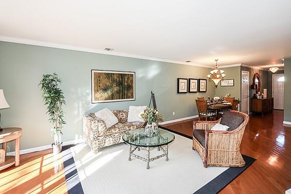 living room with dark wood-type flooring and ornamental molding