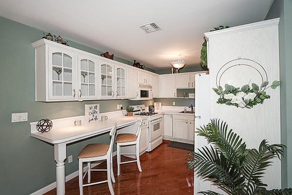 kitchen featuring white appliances, dark hardwood / wood-style flooring, sink, and white cabinets