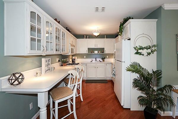 kitchen with white cabinetry, a kitchen bar, dark hardwood / wood-style flooring, and sink