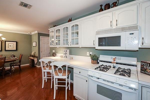 kitchen with white cabinetry, white appliances, ornamental molding, and dark hardwood / wood-style floors