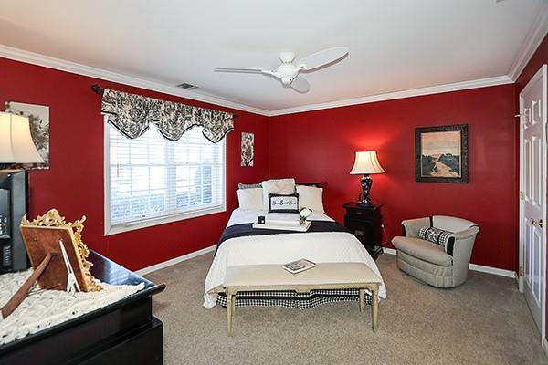 carpeted bedroom featuring crown molding and ceiling fan