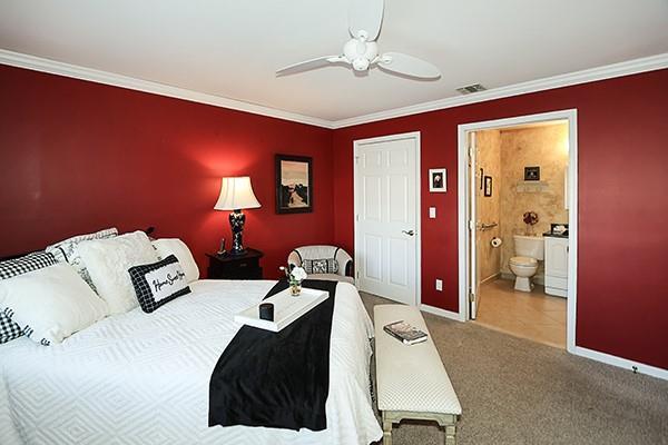 bedroom featuring connected bathroom, crown molding, ceiling fan, and carpet