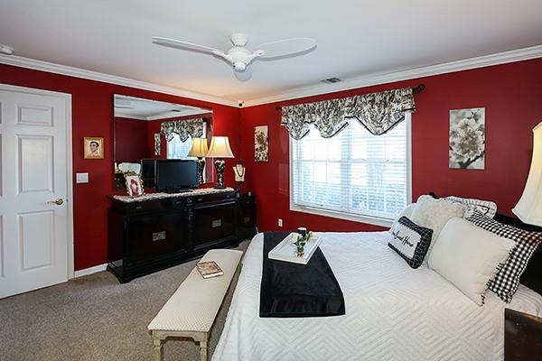 carpeted bedroom featuring crown molding and ceiling fan