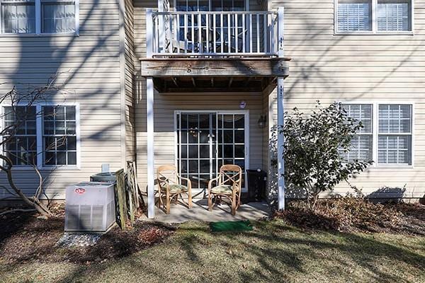 property entrance with cooling unit, a lawn, a patio, and a balcony