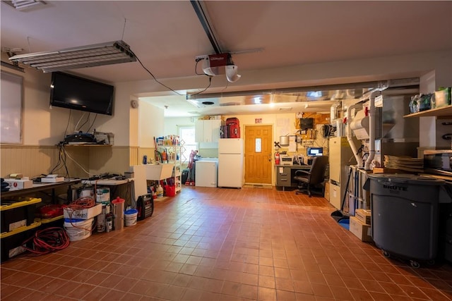 garage featuring separate washer and dryer, a garage door opener, a workshop area, and white refrigerator