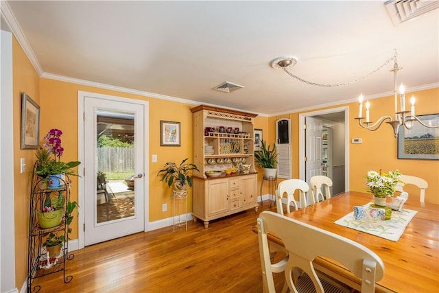 dining room with hardwood / wood-style flooring, crown molding, and a notable chandelier