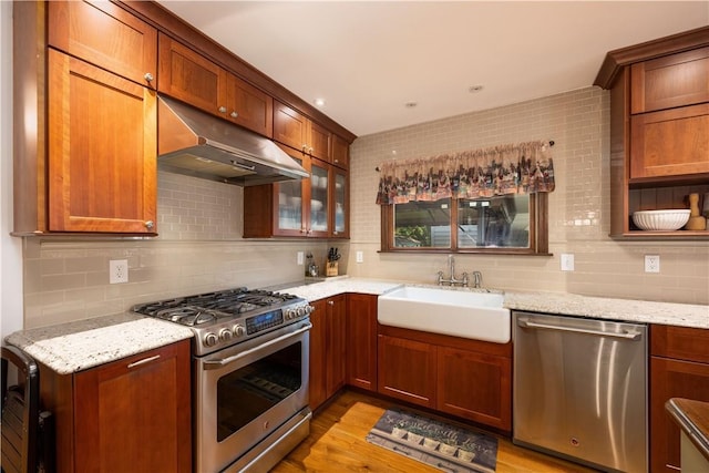 kitchen with light stone counters, sink, decorative backsplash, and appliances with stainless steel finishes