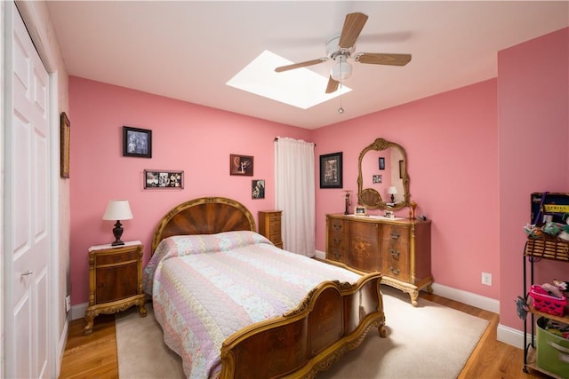 bedroom featuring a skylight, ceiling fan, and light wood-type flooring