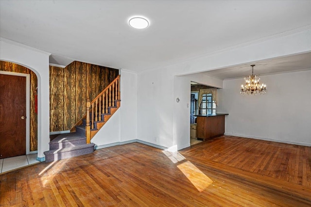 spare room with an inviting chandelier, hardwood / wood-style floors, and ornamental molding