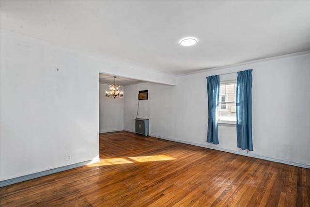 empty room with an inviting chandelier, hardwood / wood-style floors, and crown molding