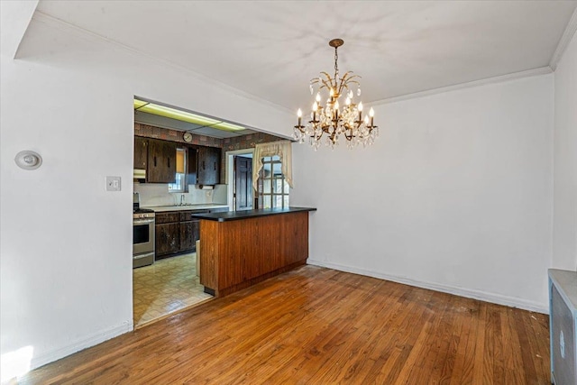 kitchen featuring ornamental molding, stainless steel range with gas cooktop, kitchen peninsula, and hardwood / wood-style floors