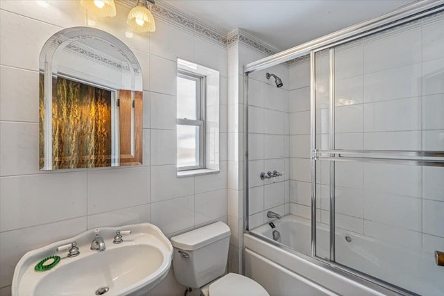 full bathroom with bath / shower combo with glass door, sink, tile walls, and toilet