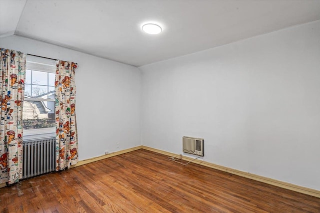 spare room with dark hardwood / wood-style flooring, radiator, heating unit, and lofted ceiling