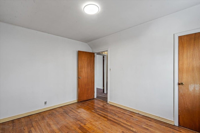 unfurnished room featuring wood-type flooring and vaulted ceiling