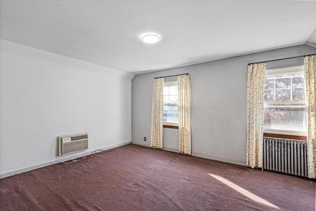 spare room featuring lofted ceiling, radiator, carpet floors, and a wall unit AC